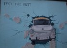 East Side Gallery, De muurschildering toont een Trabant (de kunstenaar's) emblematische auto van Oost-Duitsland, die de muur oversteekt. Deze lijkt kapot te zijn. De Trabant verlaat een donkere ruimte (het oosten) naar het licht (het westen). De datum van opening van de muur staat vermeld op het kenteken. gemaakt in 1991 door Birgit Kinder