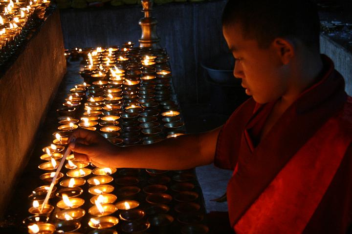 20081119-186bhutan.jpg - geconcentreerde monnik steekt boterlampjes aan in Gom Kora